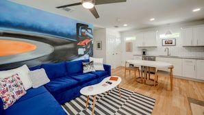A modern living room with a blue sofa, a white coffee table, and a painting on the wall. - Pristine, Private, Central, Cozy,  Fully-Equipped! (Austin)