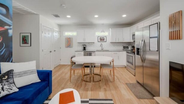 A modern kitchen with white cabinets, a stainless steel refrigerator, and a dining table with chairs. - Pristine, Private, Central, Cozy,  Fully-Equipped! (Austin)