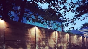 A wooden wall with a series of evenly spaced vertical slits, possibly for ventilation or security. - Pristine, Private, Central, Cozy,  Fully-Equipped! (Austin)