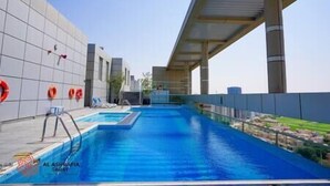 En pool med modern design, omgiven av ett takförsett område med utsikt över stadsbilden.