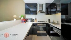 Una cucina moderna con mobili neri, elettrodomestici in acciaio inossidabile e un piano di lavoro bianco.
