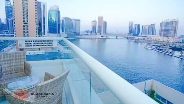A high-rise building with a view of a river and other modern buildings. - Cozy 2BR apartment in Downtown Dubai (Dubai)