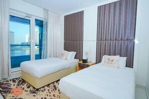 Ett hotellrum med två sängar, utsikt över staden och ett mönstrat golv.