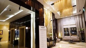 A hotel lobby with a reception desk, a seating area with a sofa and armchairs, and a large window with curtains. - Cozy 2BR apartment in Downtown Dubai (Dubai)