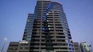 A tall, modern hotel with a curved facade, multiple balconies, and a prominent sign for a cafe. - Cozy 2BR apartment in Downtown Dubai (Dubai)