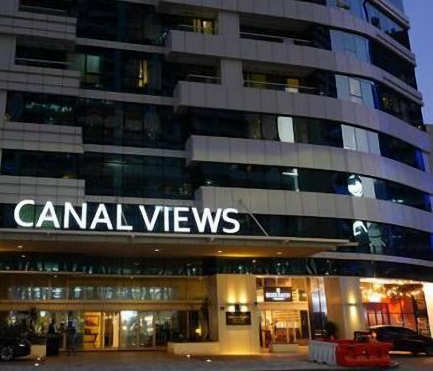 Ett hotell med flera våningar som heter ”CANAL VIEWS”, med en framträdande entré och en väl synlig skylt.