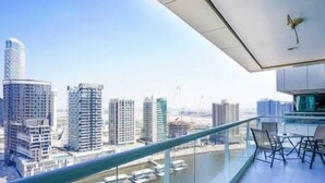 A high-rise building with a modern design, featuring a glass balcony with outdoor seating.