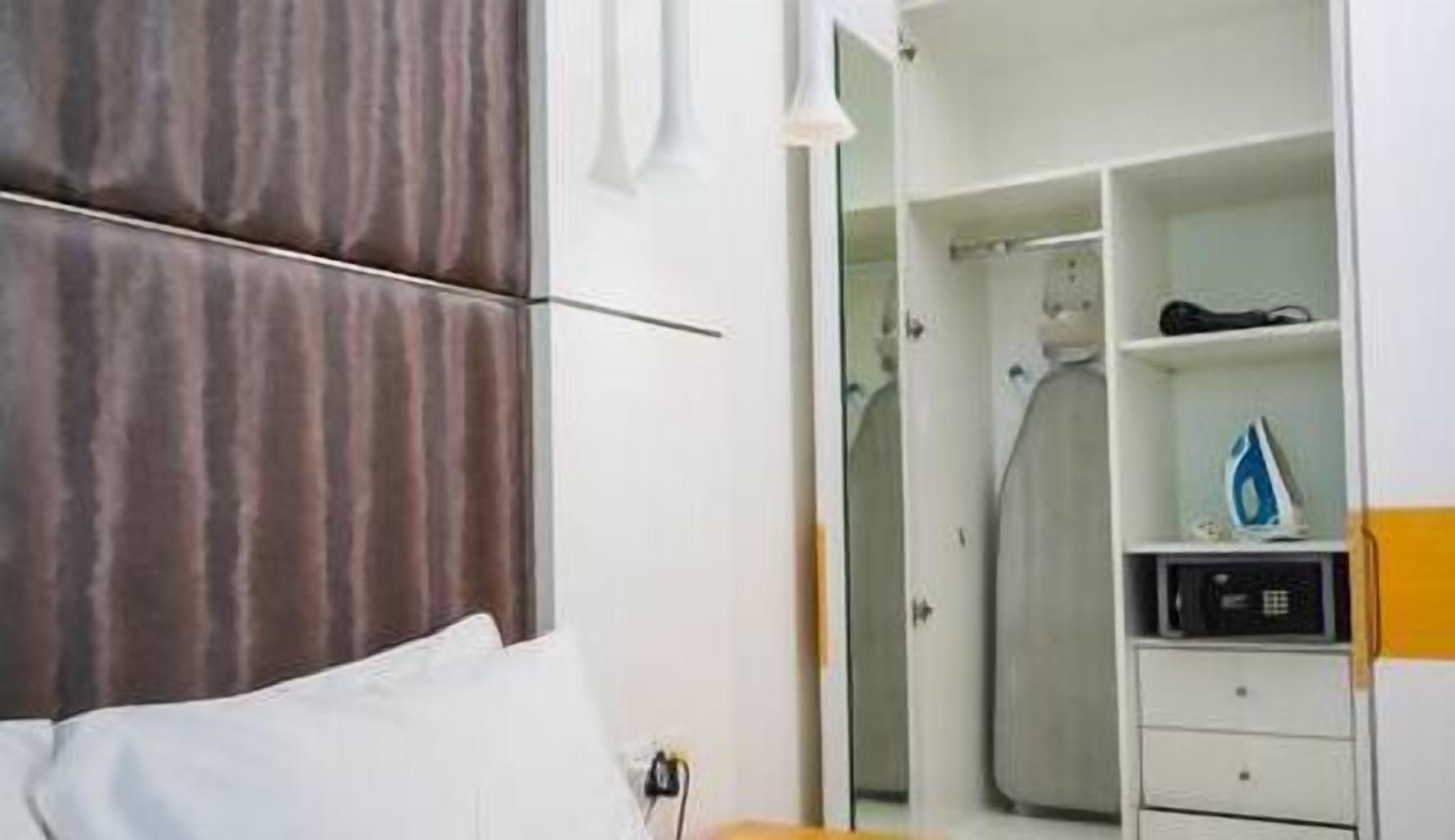 Una habitación de hotel con una cama, un armario y un escritorio pequeño con una plancha.