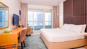 Een hotelkamer met een groot bed, een bureau met een stoel, een televisie en een raam met gordijnen.