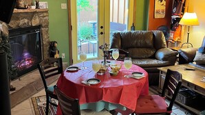 Un comedor con mantel rojo, chimenea, pared de piedra y puerta verde.