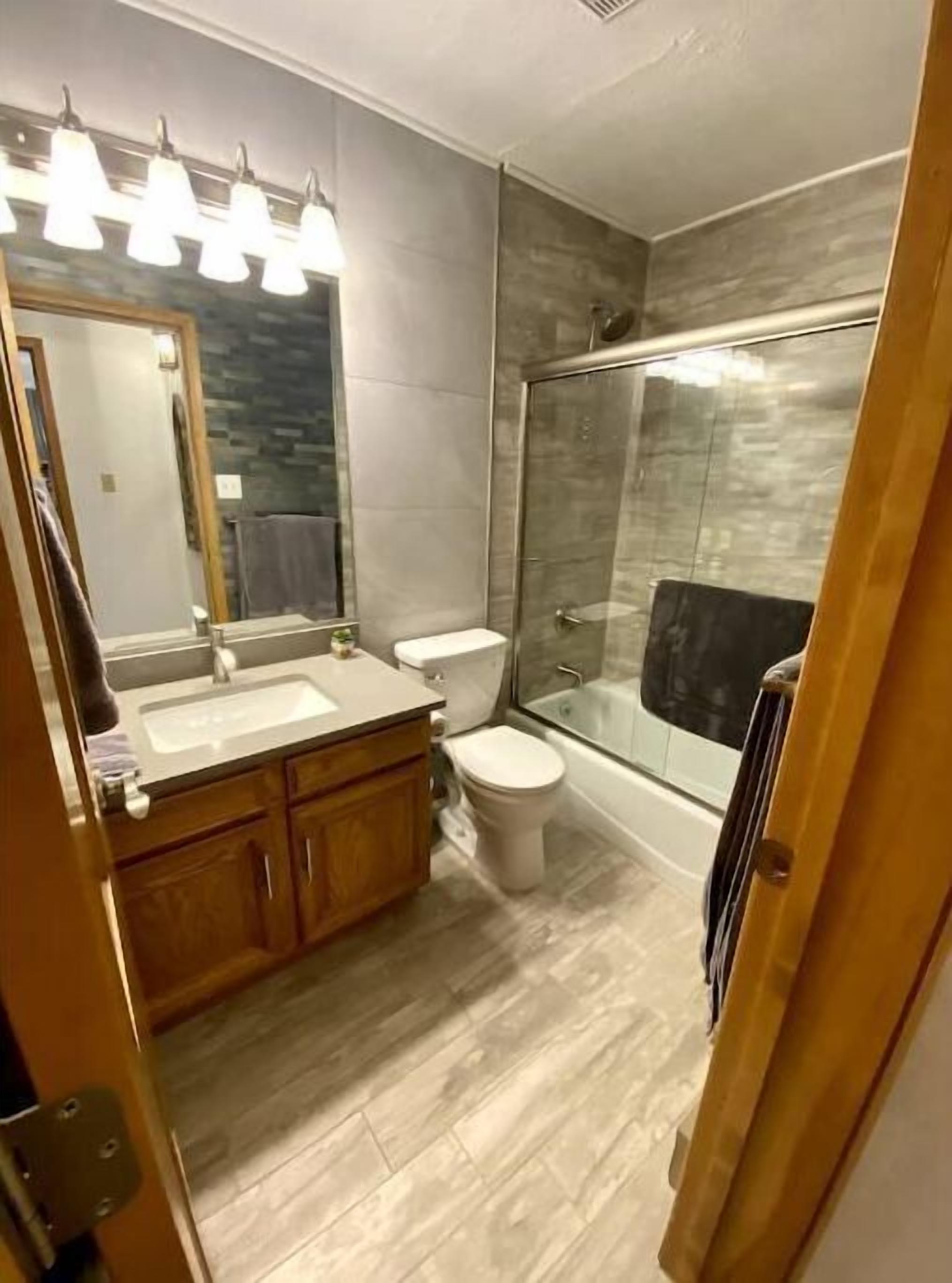 Ein modernes Badezimmer mit einer Duschkabine, einem Doppelwaschbecken und einer Toilette.