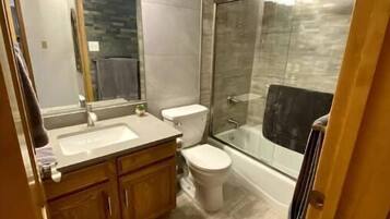 Ein modernes Badezimmer mit einer Duschkabine, einem Doppelwaschbecken und einer Toilette.
