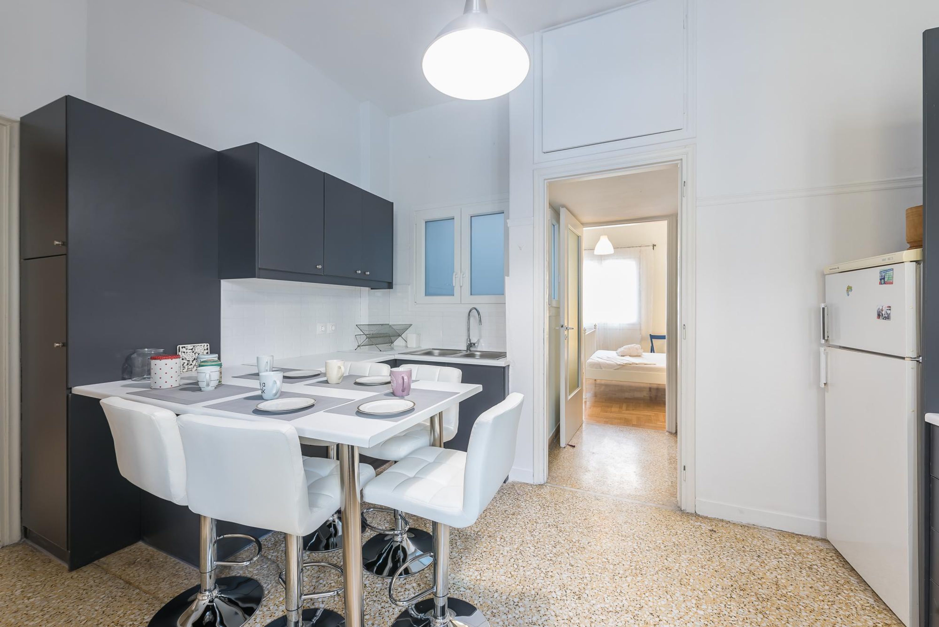 A compact kitchen with a dining area, white and dark cabinets, a white refrigerator, and a small dining table with chairs.