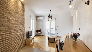 Amplia sala de estar con piso de espiga, una mesa de comedor de madera y una pared decorativa de ladrillo.