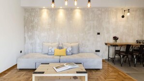 Una sala de estar moderna con un sofá gris claro, una mesa de centro de madera y un comedor con mesa y sillas de madera.