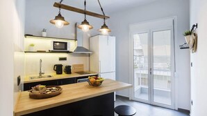 Una cocina moderna con una isla de madera, electrodomésticos de acero inoxidable y vistas al balcón.