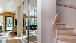 A modern interior with a wooden staircase, a glass door leading to a living area, and a view of the outdoors.