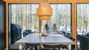 A modern dining area with a large table, chairs, and a central woven light fixture.