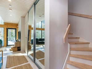 A modern interior with a wooden staircase, a glass door leading to a living area, and a view of the outdoors. - Villa väiski by Interhome (Heinola)