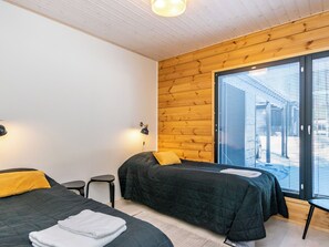 A bedroom with two beds, a window with blinds, and a wooden ceiling. - Villa väiski by Interhome (Heinola)