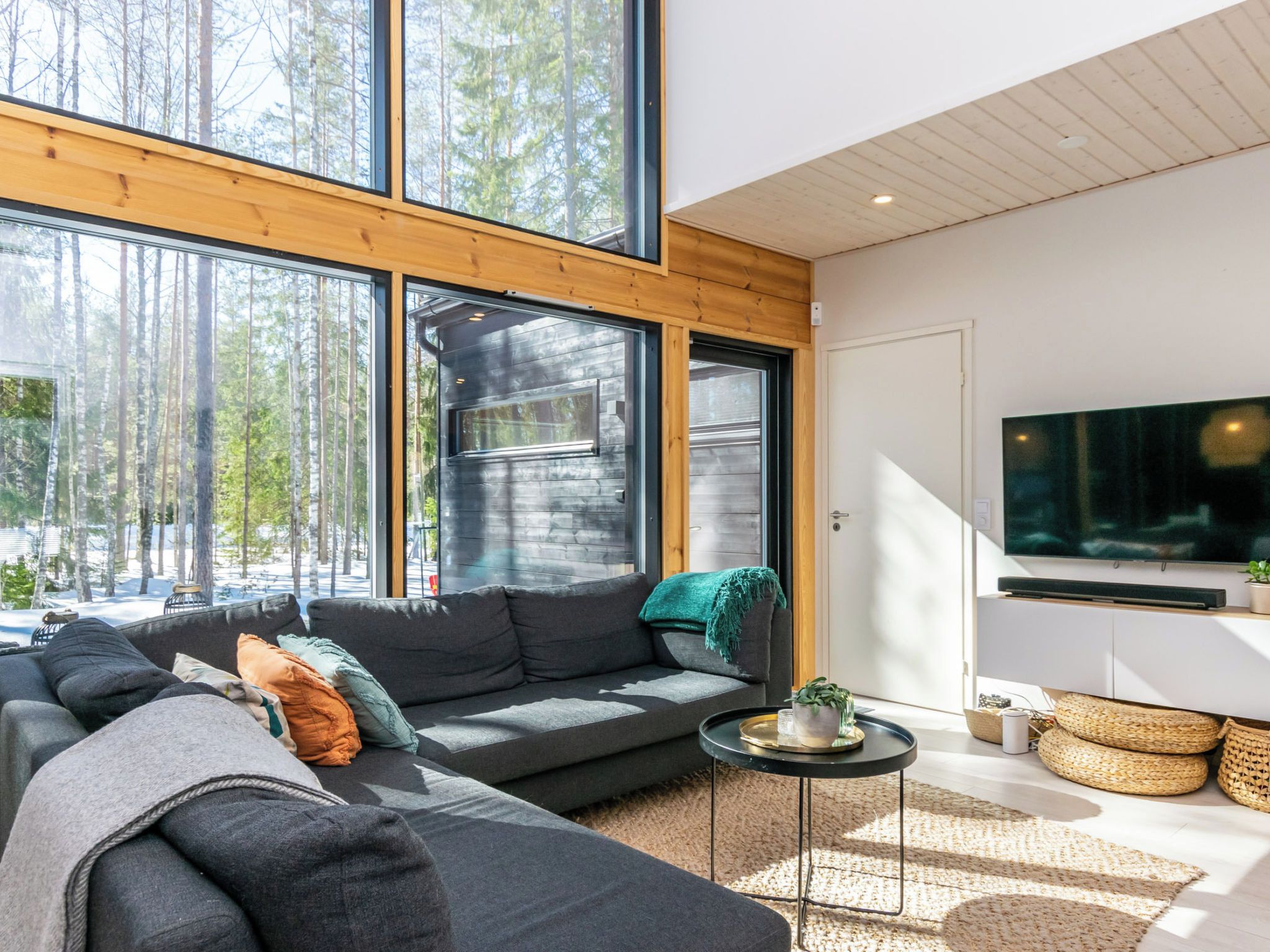 A modern living room with a large window, a sofa, a coffee table, and a flat-screen TV.