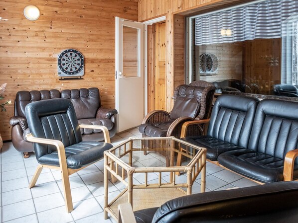 A cozy room with wooden walls, leather sofas, and a dartboard.
