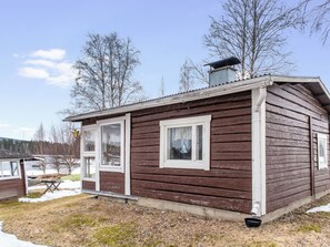 Une petite cabane en bois avec une cheminée, une fenêtre et une porte.