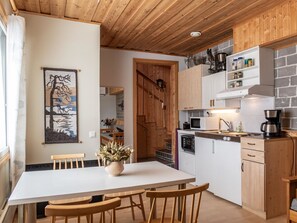 A compact kitchen with wooden cabinets, a white countertop, and a dining area with a table and chairs.