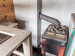Un poêle à bois avec une cheminée, une table et un tuyau d’arrosage vert.