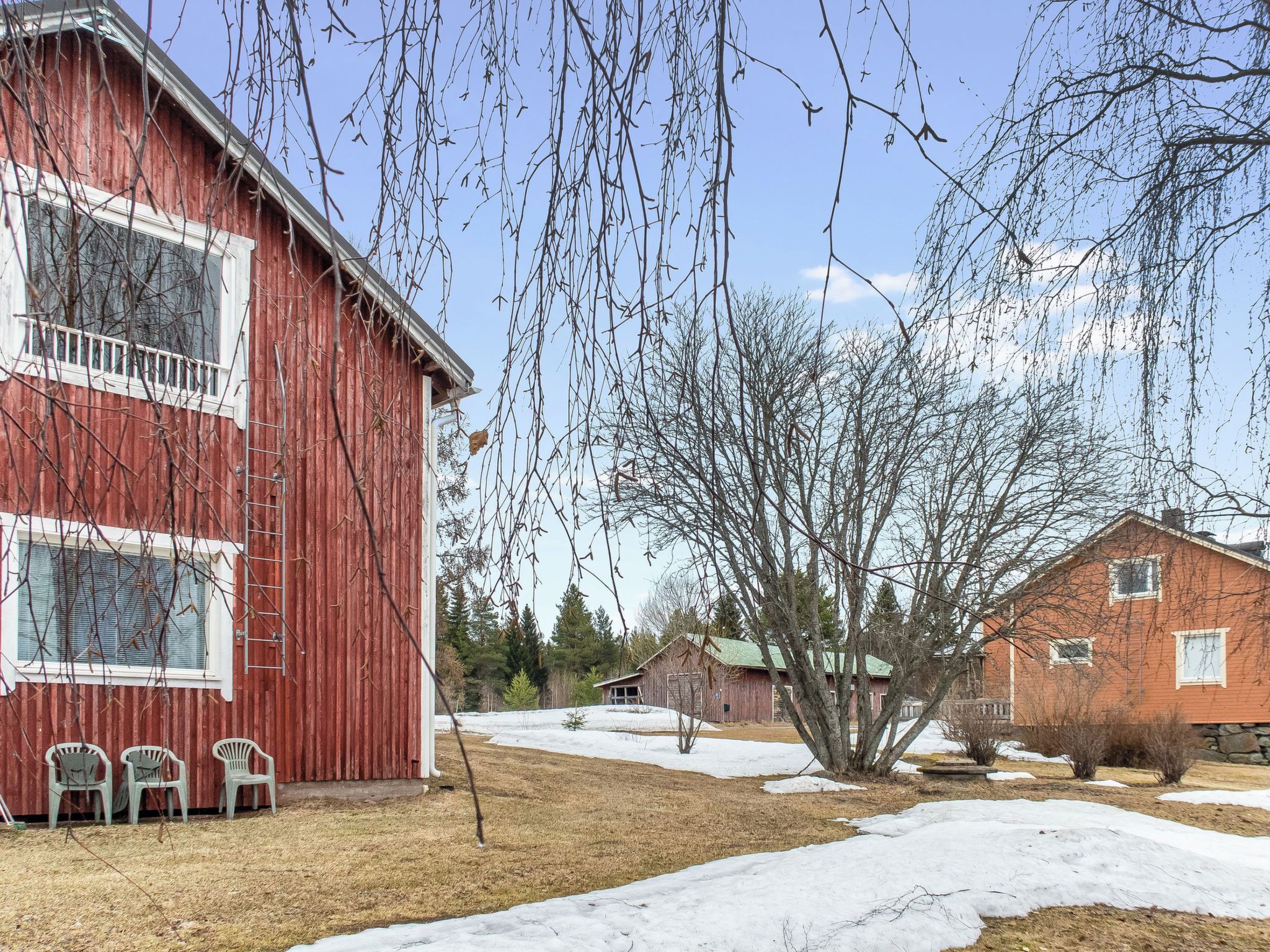 A red barn with a white window, a tree in the foreground, and a snow-covered ground.