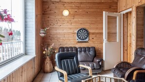 Tunnelmallinen huone, jossa on puuseinät, tikanheittoalusta ja ikkunalaudalla kukkia.