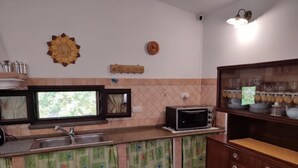 Eine Küche mit Spüle, Mikrowelle und einem Holzschrank mit Gläsern.