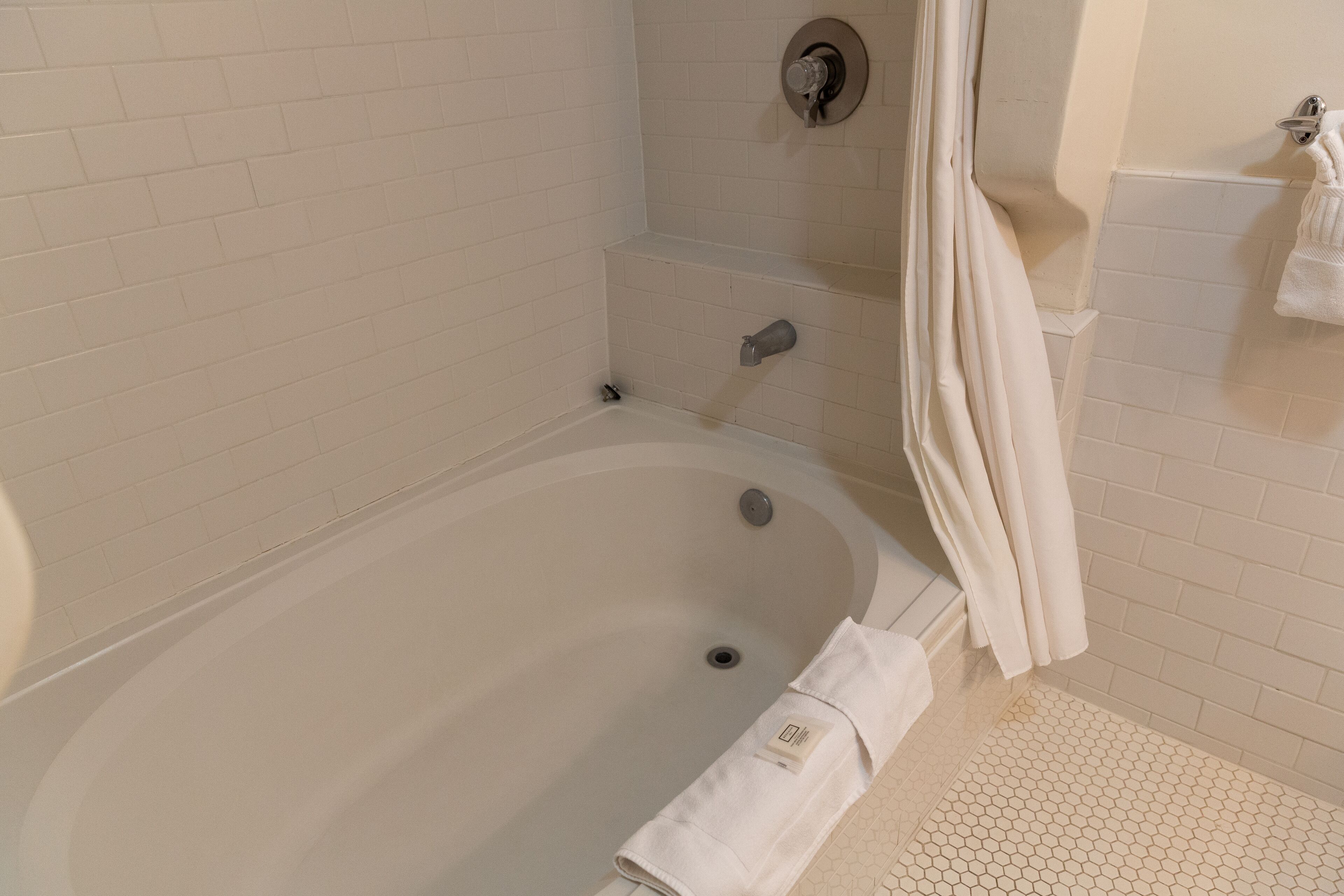 A bathroom with a bathtub, a towel rack, and a shower curtain.