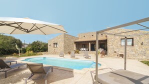 A stone building with a pool, outdoor seating, and an umbrella. - Bellpuig by Interhome (Artà)