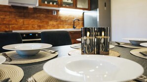 Une cuisine moderne avec des meubles en bois, un four encastré et une table à manger dressée avec des assiettes, des couverts et un chandelier.