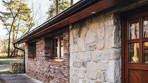 Une cabane rustique avec une façade en pierre et des cadres de fenêtres en bois, des fondations en pierre et une porte en bois.
