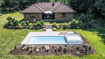 Una casa a due piani con piscina, serra e un giardino curato.