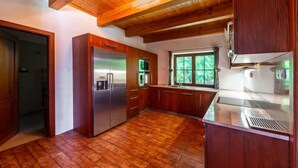 Une cuisine moderne avec un plancher en bois, un réfrigérateur en acier inoxydable et une fenêtre donnant sur un paysage verdoyant.