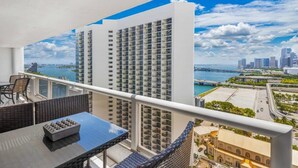 A balcony with a view of a city skyline, a body of water, and a bridge. - Classic Waterfront Apt | Bay Views | StayCozy (Miami)