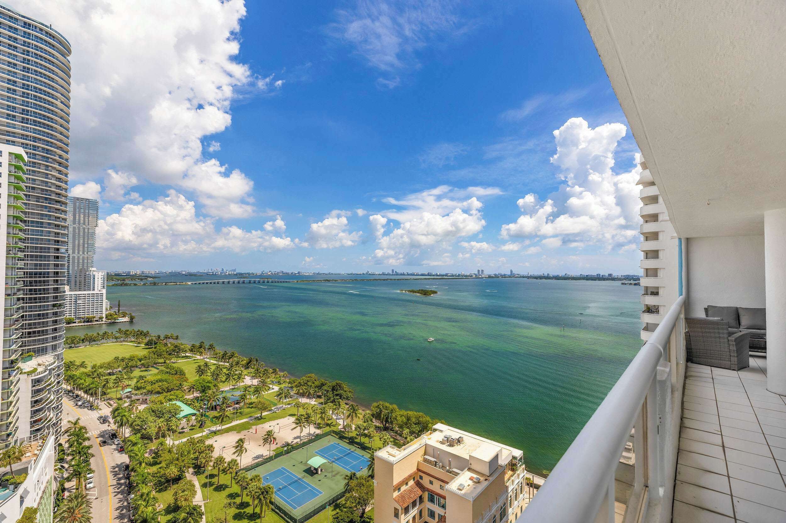 A high-rise building with a view of a marina and a clear sky.