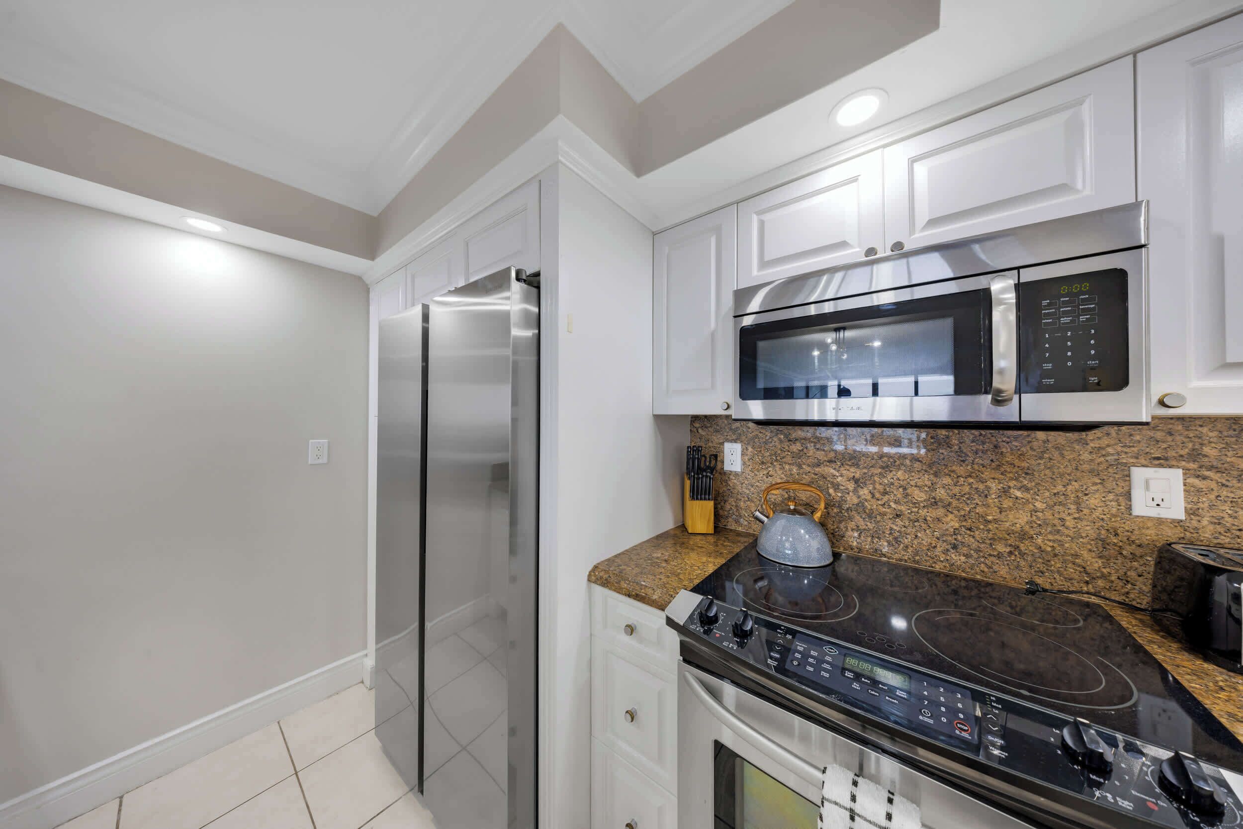 A modern kitchen with white cabinetry, stainless steel appliances, and granite countertops.
