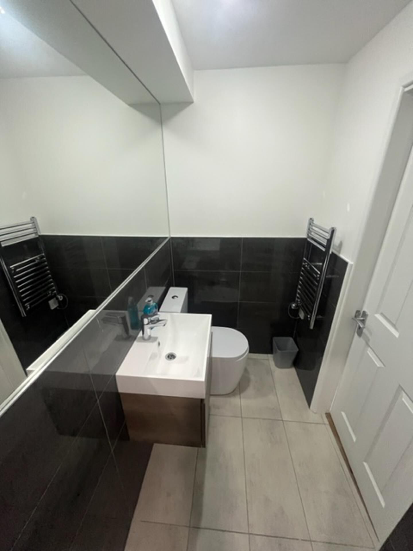 Een kleine badkamer met een wit wastafel, toilet en spiegel.