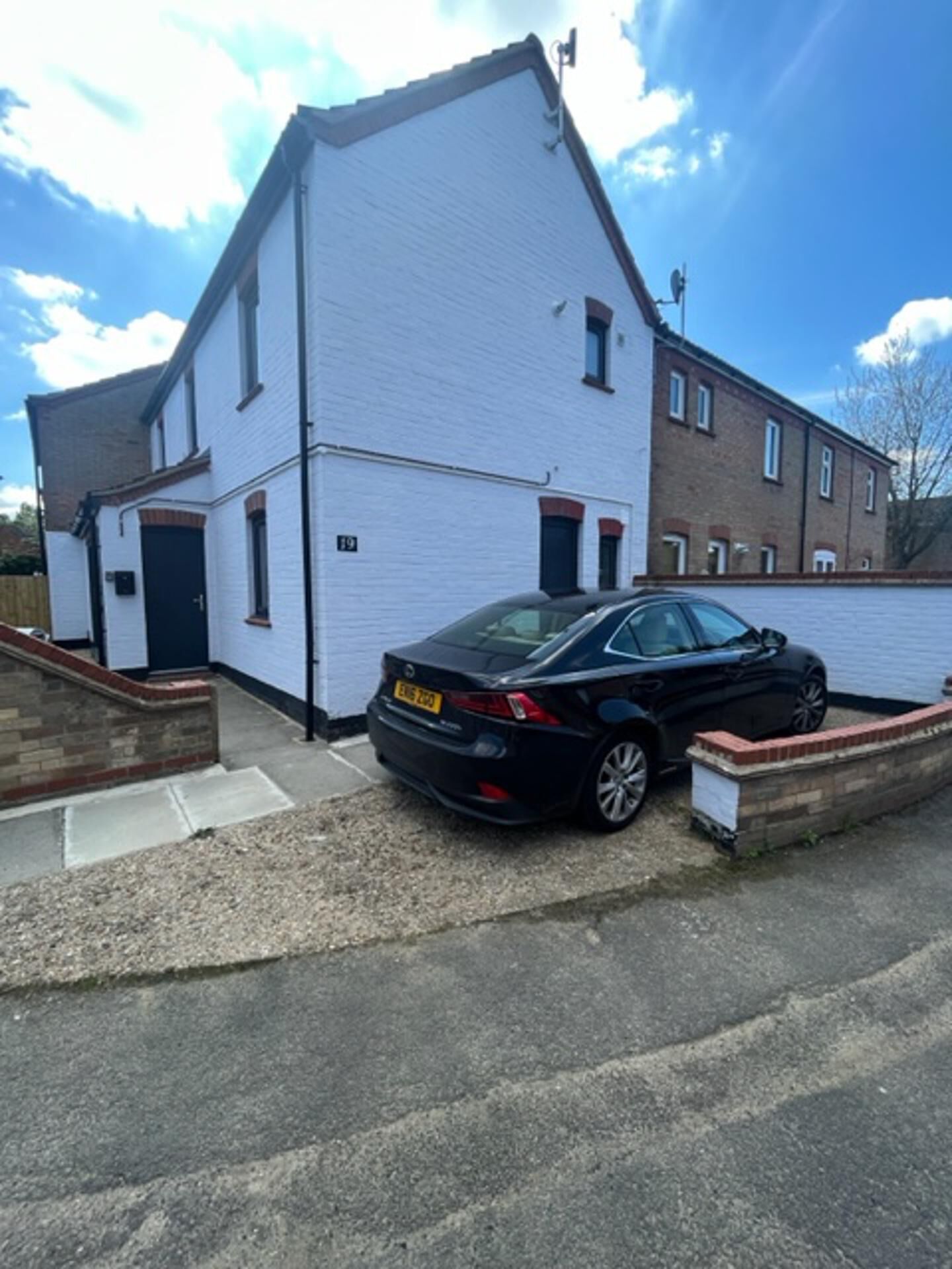 A two-story building with a white exterior and a black car parked in front.