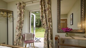 A bedroom with a bed, a chair, a dresser, a mirror, and curtains. - Luxury Highland Hideaway with Hot Tub by LochNess (Inverness)