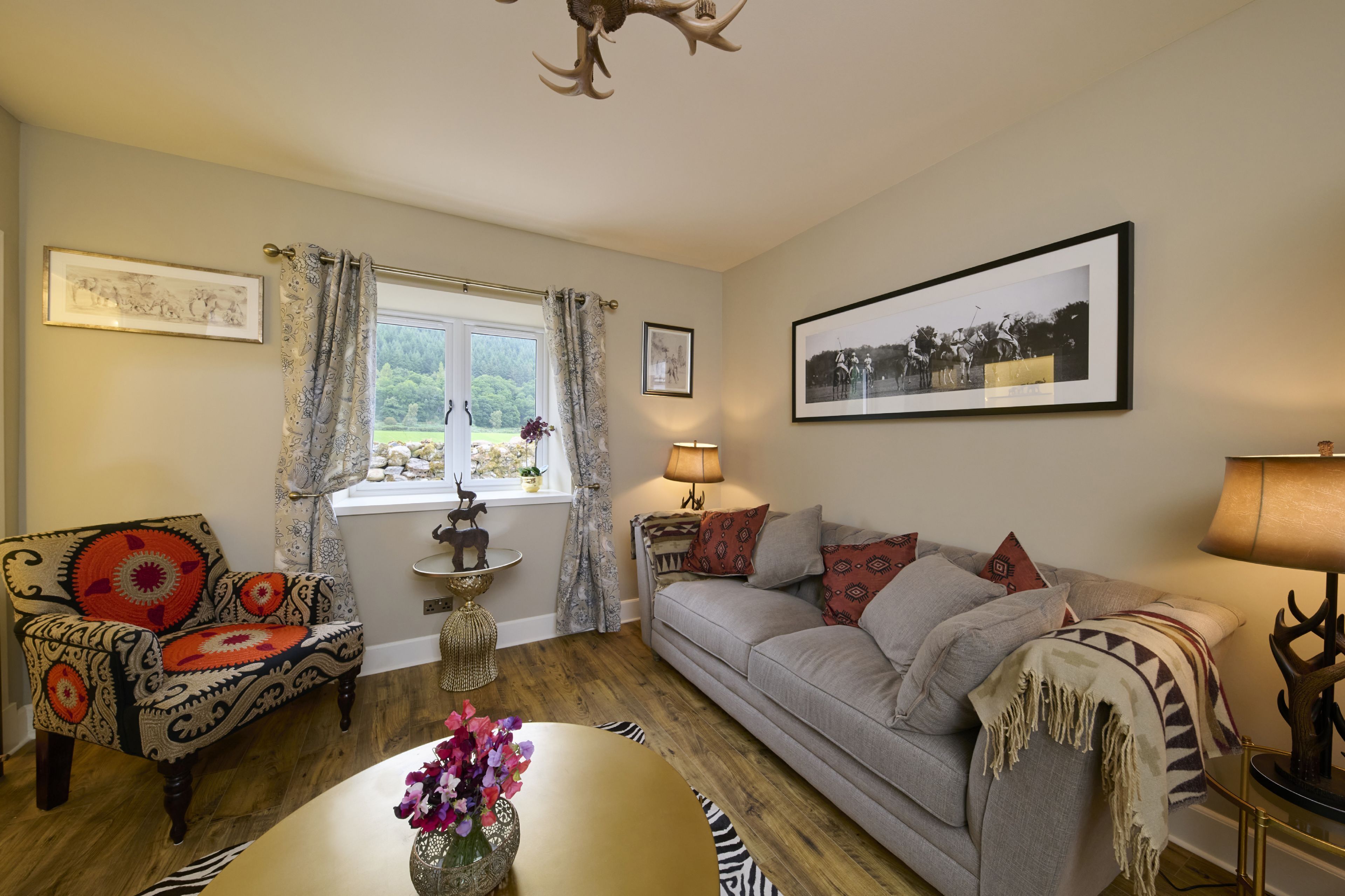 A cozy living room with a sofa, armchair, and a table with flowers.