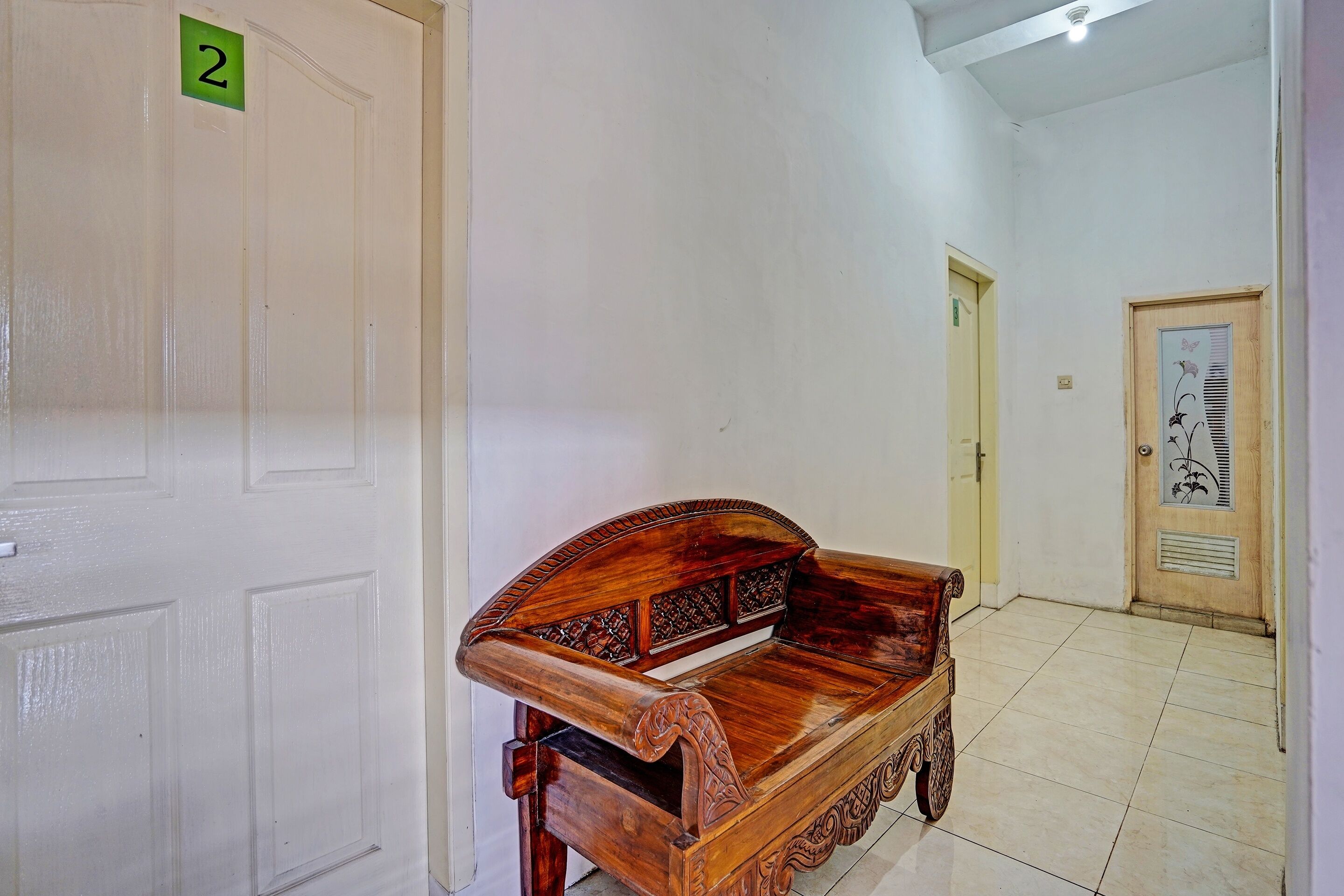 A hallway with a wooden bench, a door labeled '2', and a door with a floral design.