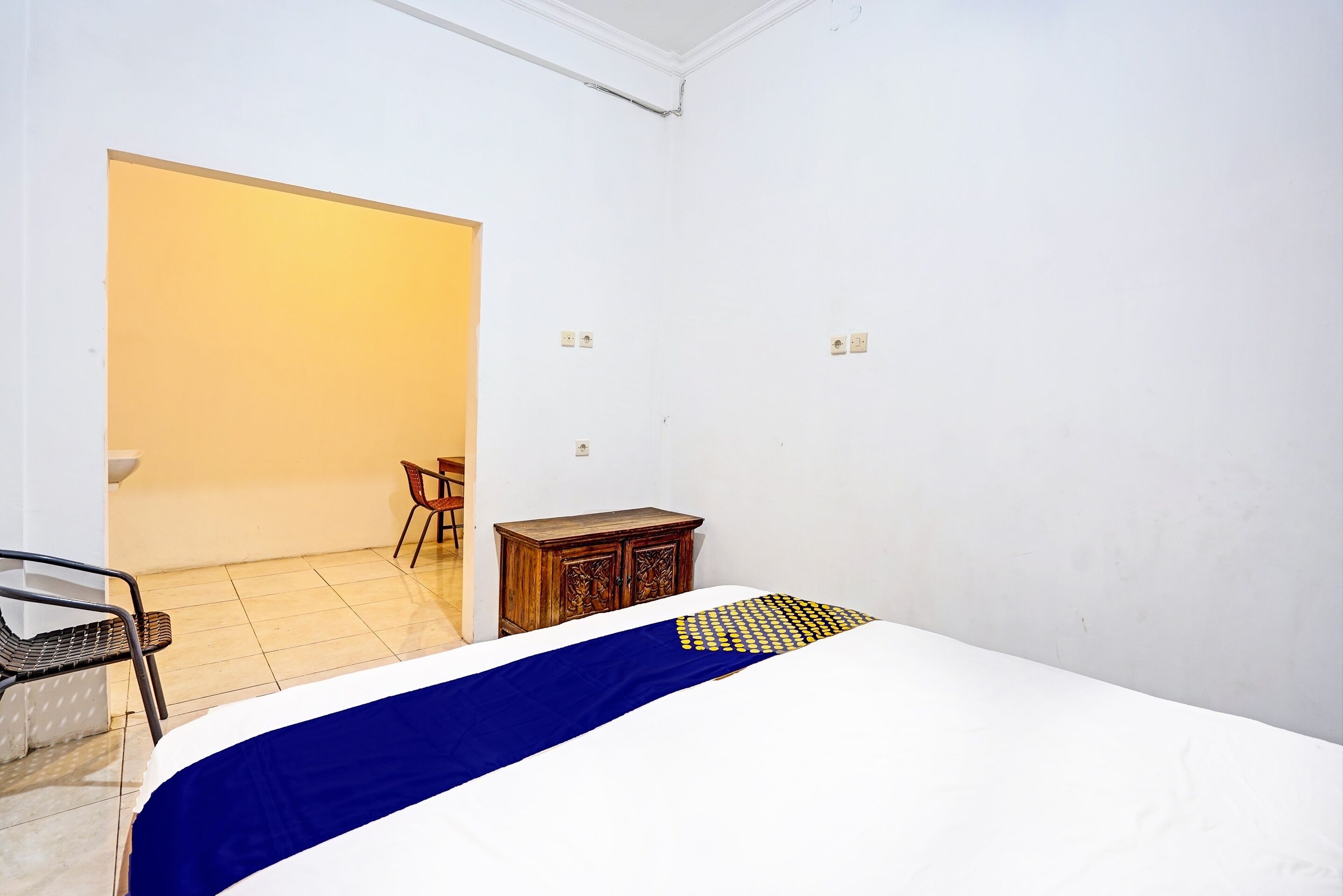 A bedroom with a bed, a wooden cabinet, a chair, and a small table.