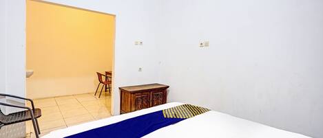 A bedroom with a bed, a wooden cabinet, a chair, and a small table.