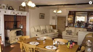 Una sala acogedora con una mesa de comedor de madera, dos sofás y una zona de cocina con estufa.