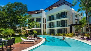 A modern hotel with a swimming pool, outdoor seating, and lush landscaping. - Room fully equipped Spa and gym free (Tulum)